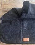 Anthracite extra-long trail-riding saddle pad with a dark lambskin roll, flat on wood
