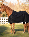 Chestnut horse in the paddock wearing a black cooler in 100% wool