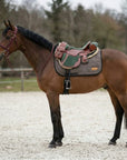 Bruin paard met een extra lang trekzadeldek onder een trekzadel met zadeltassen