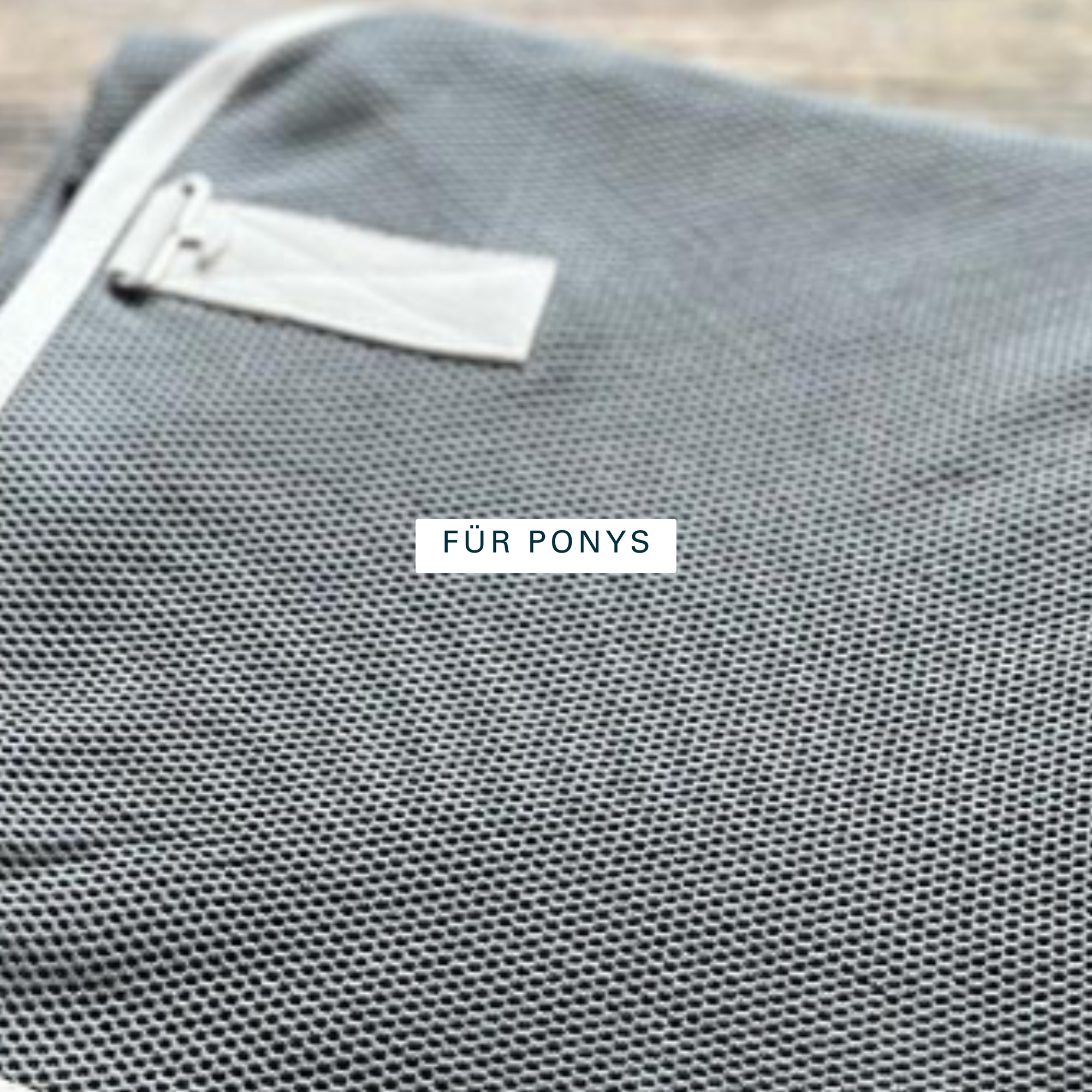 Grey mesh fabric of an organic cotton fly sheet with a light-coloured binding, for ponies