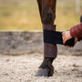 Hånd vikler en sort bandage over et bordeauxrødt CHVX*N bandageunderlag i merinould