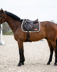 Cavallo baio in campo ostacoli con un sottosella da salto marrone scuro e profilo color crema